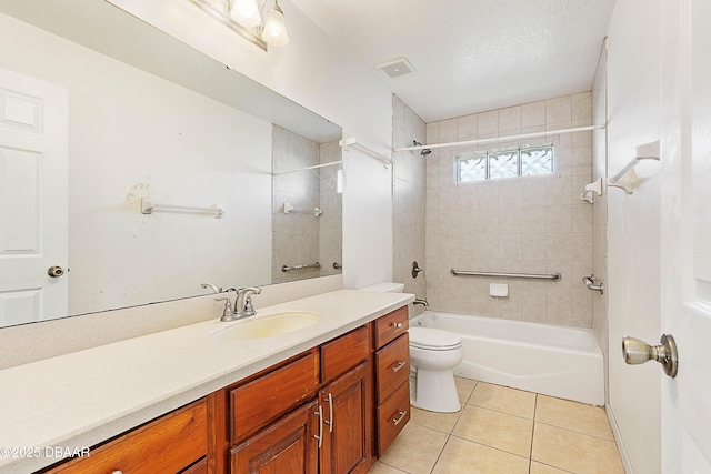 full bathroom with tile patterned flooring, toilet, tiled shower / bath, a textured ceiling, and vanity