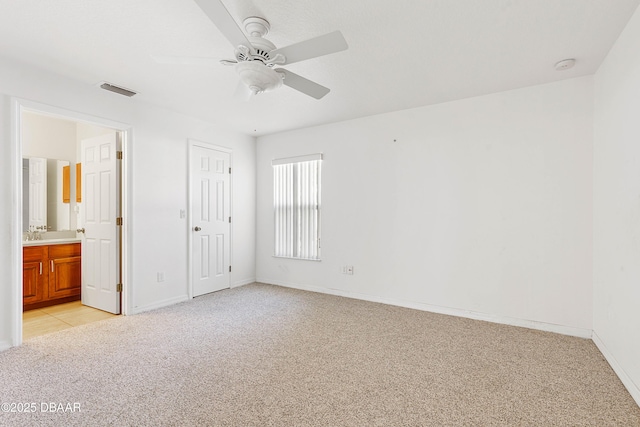 unfurnished bedroom featuring ceiling fan, ensuite bath, and light colored carpet