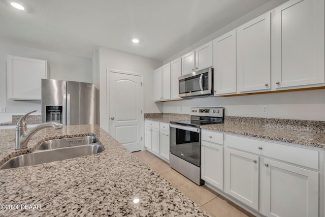 350 Sunset Point Dr, Ormond Beach, FL 32174 - kitchen featuring appliances with stainless steel finishes, a sink, light tile patterned floors, white cabinetry, and light stone countertops