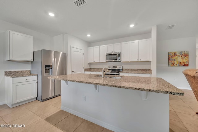 kitchen featuring stainless steel appliances, sink, a breakfast bar, a kitchen island with sink, and white cabinets