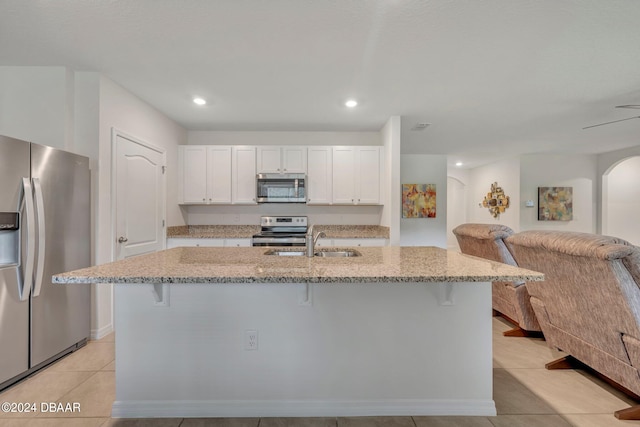 kitchen with white cabinets, stainless steel appliances, an island with sink, and a breakfast bar