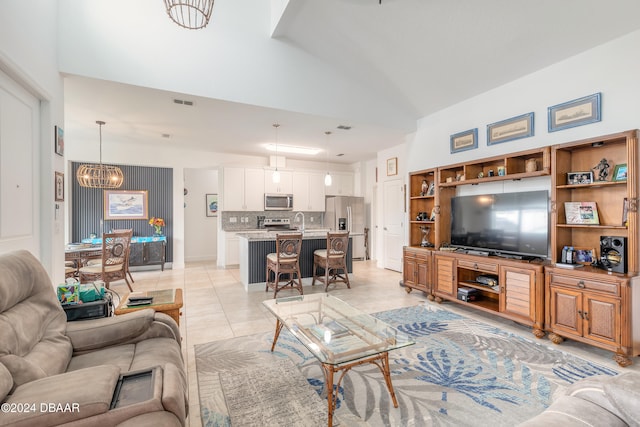 tiled living room with a chandelier, sink, and high vaulted ceiling