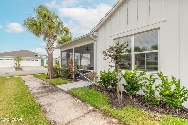 entrance to property with a garage, a yard, and ceiling fan