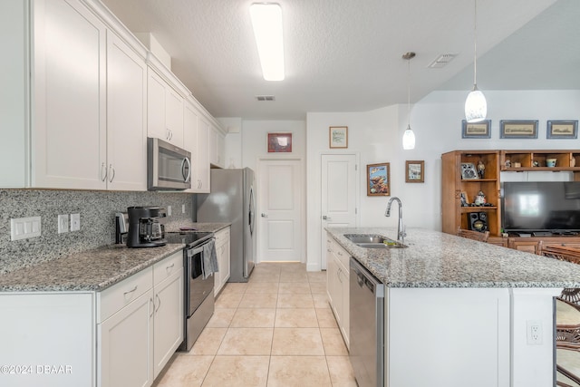 kitchen with white cabinetry, appliances with stainless steel finishes, decorative light fixtures, light stone countertops, and sink