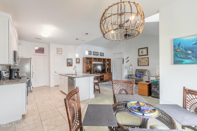 tiled dining area with sink, vaulted ceiling, and an inviting chandelier