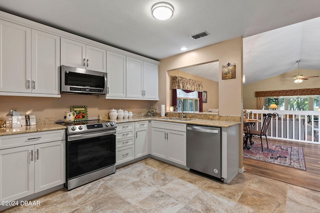 kitchen featuring stainless steel appliances, white cabinetry, sink, and vaulted ceiling