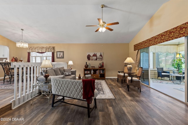 living room featuring ceiling fan with notable chandelier, dark wood-type flooring, and vaulted ceiling