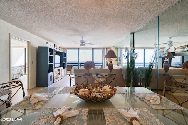 dining room featuring expansive windows, a textured ceiling, ceiling fan, and light hardwood / wood-style flooring