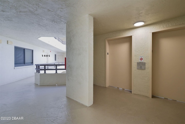 interior space with elevator, a textured ceiling, and a skylight