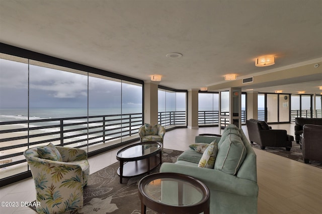 living room featuring a view of the beach, a water view, floor to ceiling windows, and ornamental molding