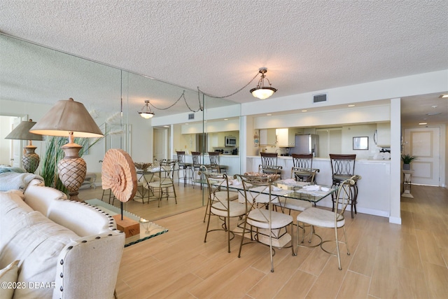 dining area with light wood-type flooring and a textured ceiling