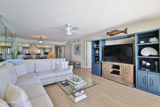 living room with hardwood / wood-style flooring, ceiling fan, and a textured ceiling