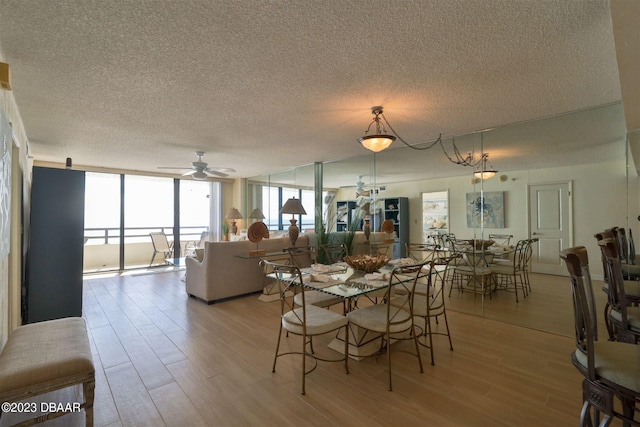 dining room featuring expansive windows, light hardwood / wood-style floors, ceiling fan, and a textured ceiling