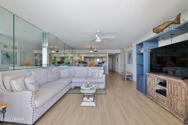 living room featuring light wood-type flooring, a textured ceiling, and ceiling fan