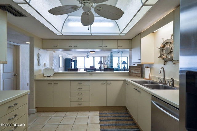 kitchen featuring cream cabinets, dishwasher, sink, ceiling fan, and light tile patterned flooring