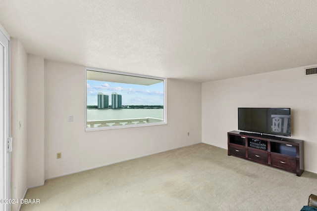 unfurnished living room with light colored carpet and a textured ceiling