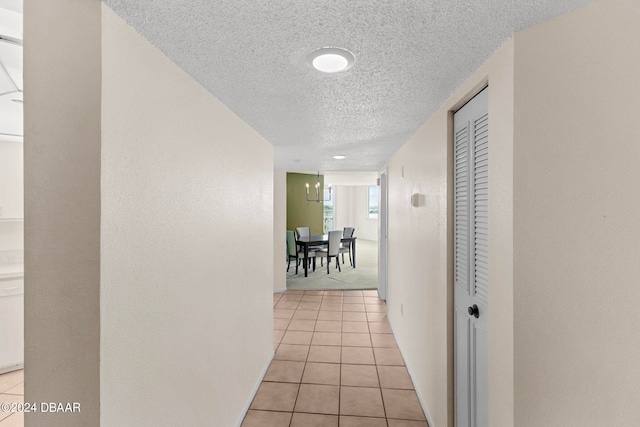 corridor featuring a textured ceiling and light tile patterned floors