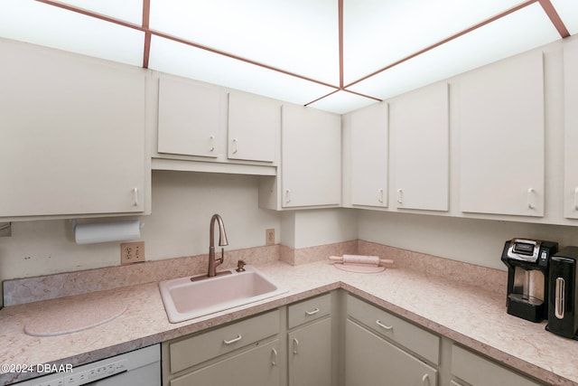 kitchen featuring white dishwasher, white cabinetry, and sink