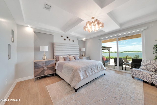 bedroom featuring access to exterior, a notable chandelier, a water view, and light hardwood / wood-style flooring