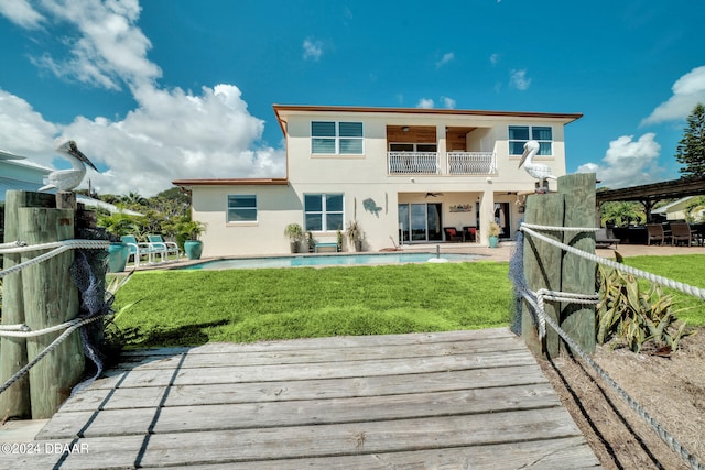 back of property with a swimming pool, a yard, and a balcony