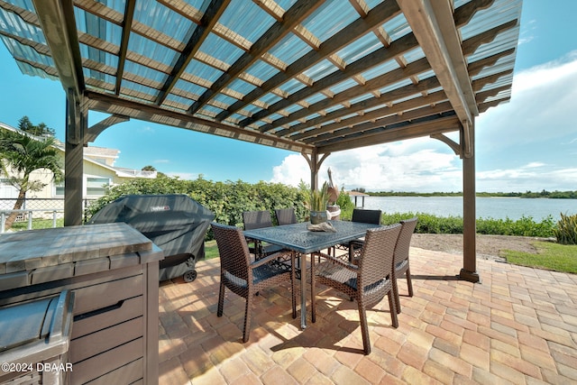 view of patio with area for grilling, a water view, and a pergola