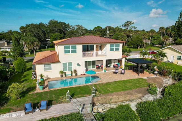 rear view of property featuring a lawn, a balcony, a gazebo, and a patio area