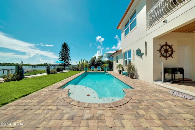 view of swimming pool with a patio, a lawn, and a water view