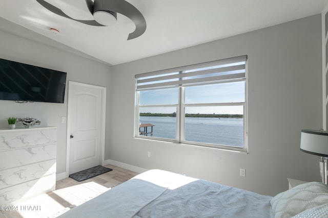 bedroom featuring ceiling fan, a water view, and light hardwood / wood-style flooring