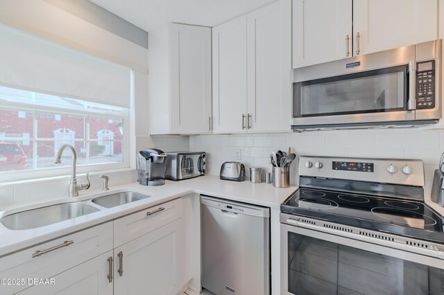 kitchen with white cabinets, appliances with stainless steel finishes, sink, and tasteful backsplash