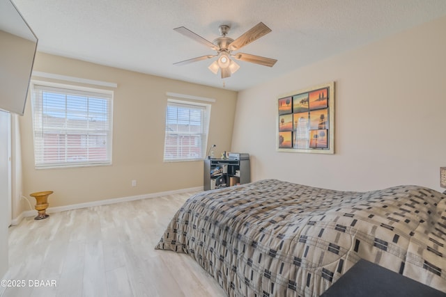 bedroom with ceiling fan, a textured ceiling, and light hardwood / wood-style flooring