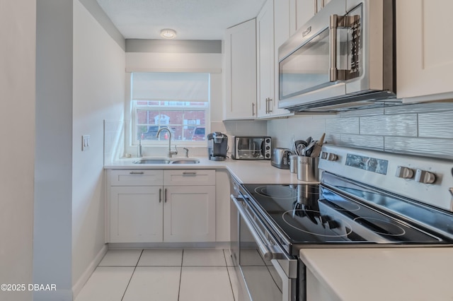 kitchen with light tile patterned floors, stainless steel appliances, decorative backsplash, white cabinets, and sink