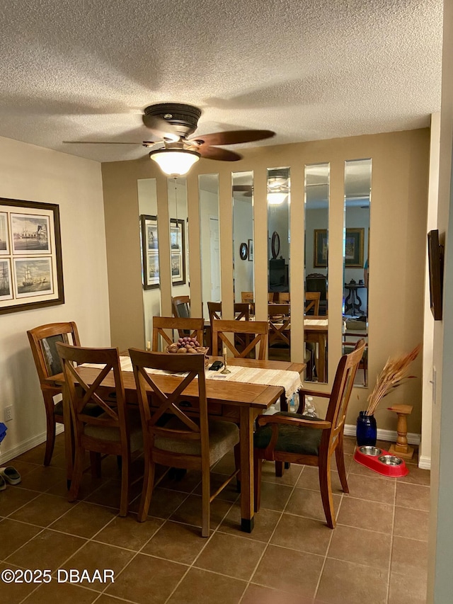 dining space featuring ceiling fan, baseboards, a textured ceiling, and dark tile patterned flooring