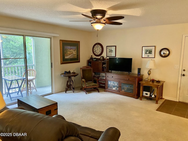 living area featuring a ceiling fan, carpet, a textured ceiling, and baseboards