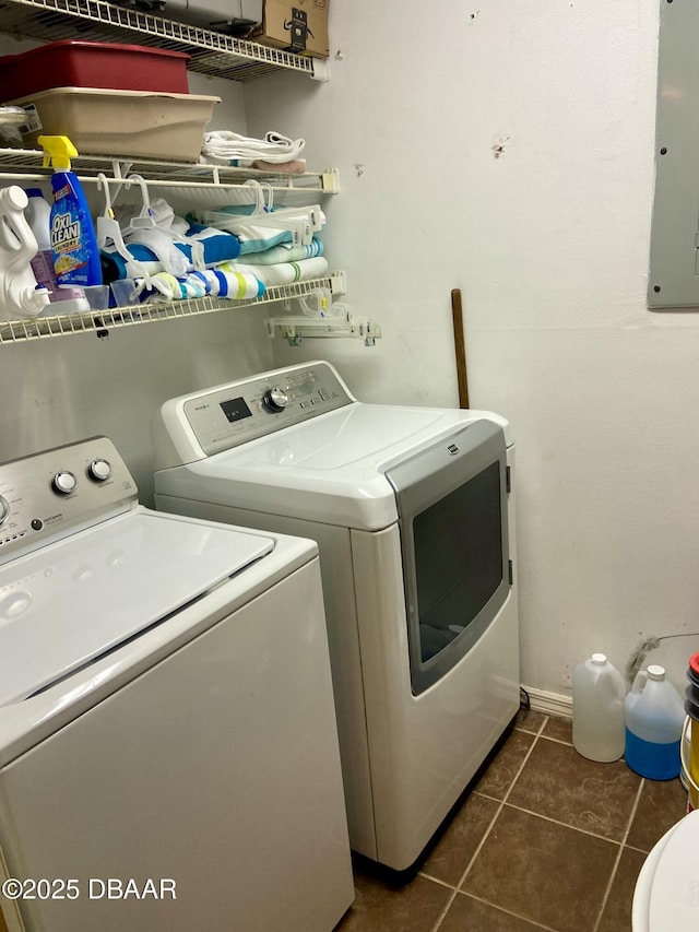 clothes washing area featuring laundry area, electric panel, dark tile patterned flooring, and washing machine and clothes dryer