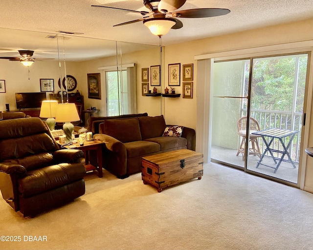 living area with light carpet, ceiling fan, and a textured ceiling