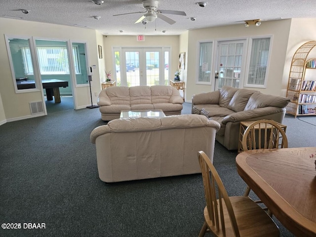 living room featuring visible vents, dark carpet, a textured ceiling, and french doors