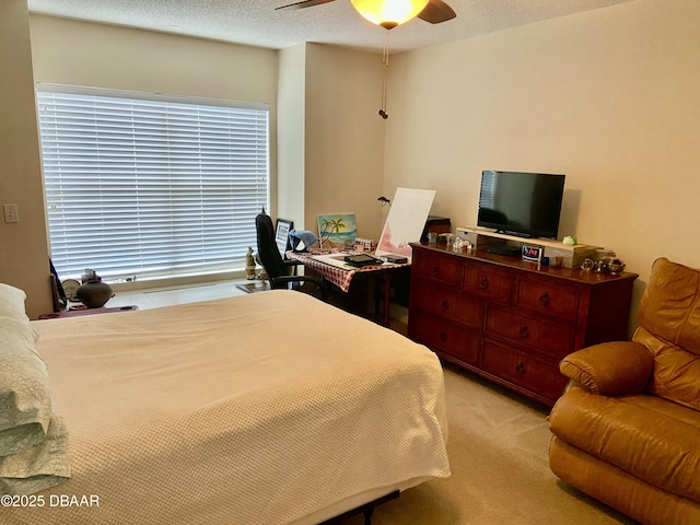 bedroom featuring light colored carpet, ceiling fan, and a textured ceiling