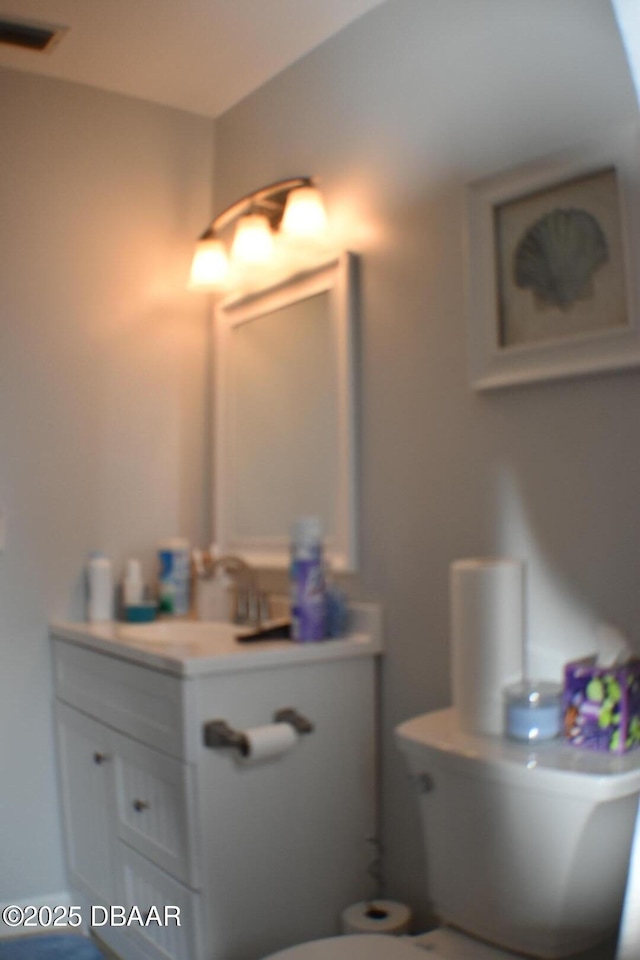 half bathroom featuring visible vents, toilet, and vanity