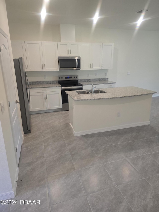 kitchen with white cabinetry, sink, stainless steel appliances, light stone counters, and a center island with sink