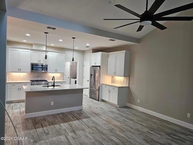 kitchen featuring an island with sink, sink, stainless steel appliances, and white cabinetry