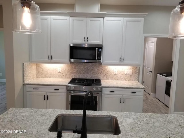 kitchen featuring white cabinets, sink, light stone counters, and stainless steel appliances