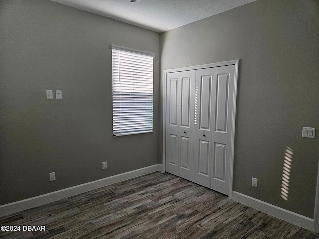 unfurnished bedroom with dark hardwood / wood-style flooring and a closet