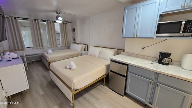 bedroom with light wood-type flooring and stainless steel fridge