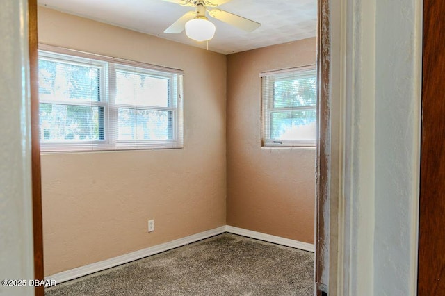 empty room featuring a ceiling fan, a textured wall, plenty of natural light, and baseboards