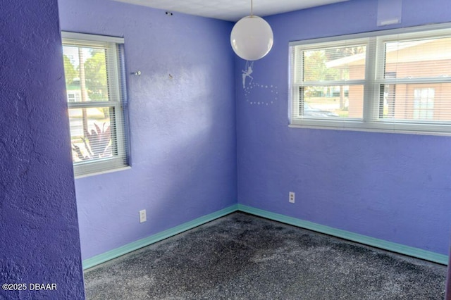 empty room featuring a textured wall and baseboards