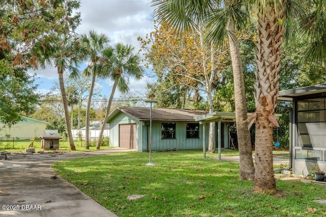 view of front of property featuring a detached garage, fence, driveway, board and batten siding, and a front yard