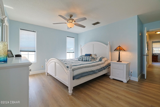 bedroom with hardwood / wood-style floors, ceiling fan, and multiple windows