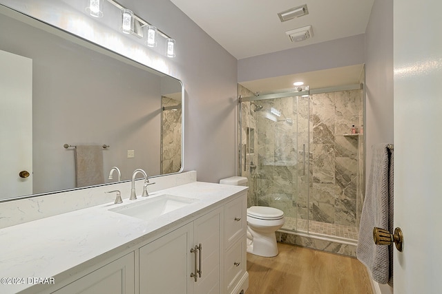 bathroom featuring wood-type flooring, vanity, toilet, and an enclosed shower