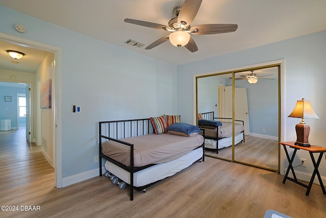 bedroom featuring light hardwood / wood-style flooring, ceiling fan, and a closet