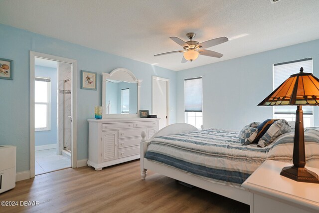 bedroom with ceiling fan, connected bathroom, light hardwood / wood-style flooring, and a textured ceiling